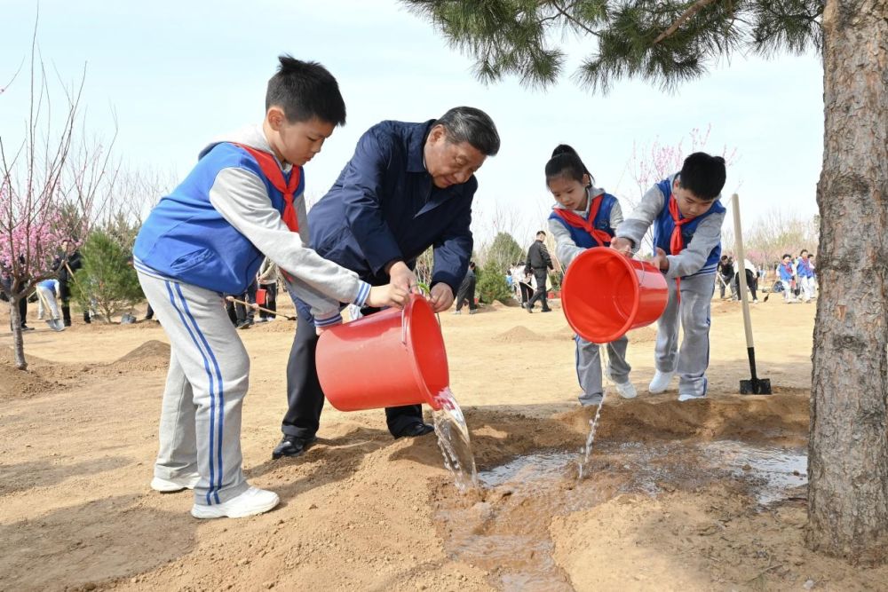 2025年4月3日，习近平总书记等来到北京市丰台区永定河畔参加首都义务植树活动。这是习近平总书记同少先队员一起给刚栽下的树苗浇水。新华社记者 谢环驰 摄